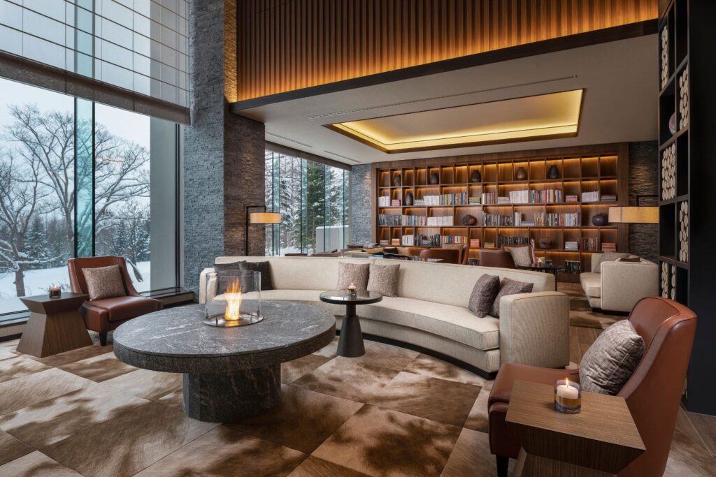The fireside lounge and library overlooking a snowy forest at Higashiyama Niseko Village