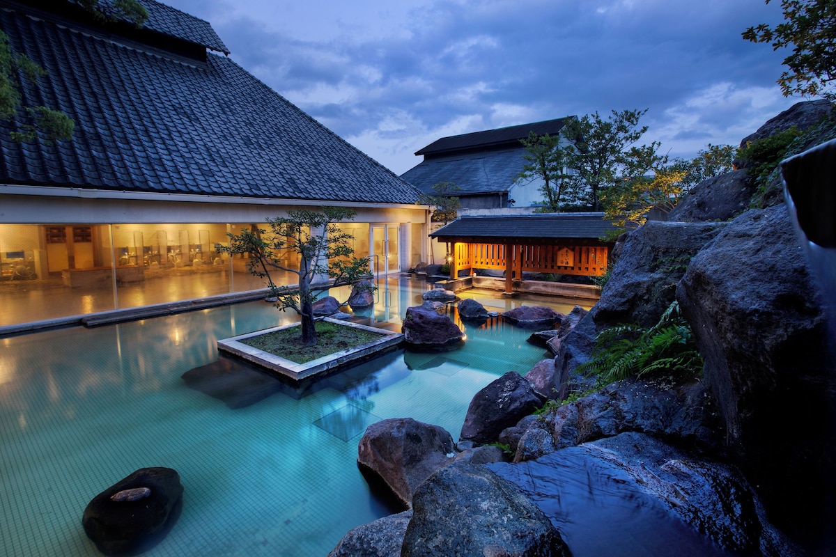 Outdoor hot-spring bath and tiled roofs at dusk at Hotel Shiragiku