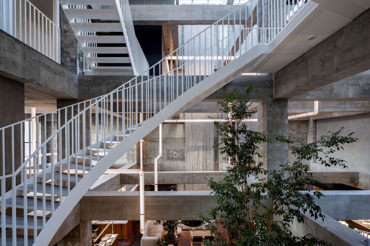 Exposed concrete atrium and bridges inside SHIROIYA HOTEL Heritage Tower