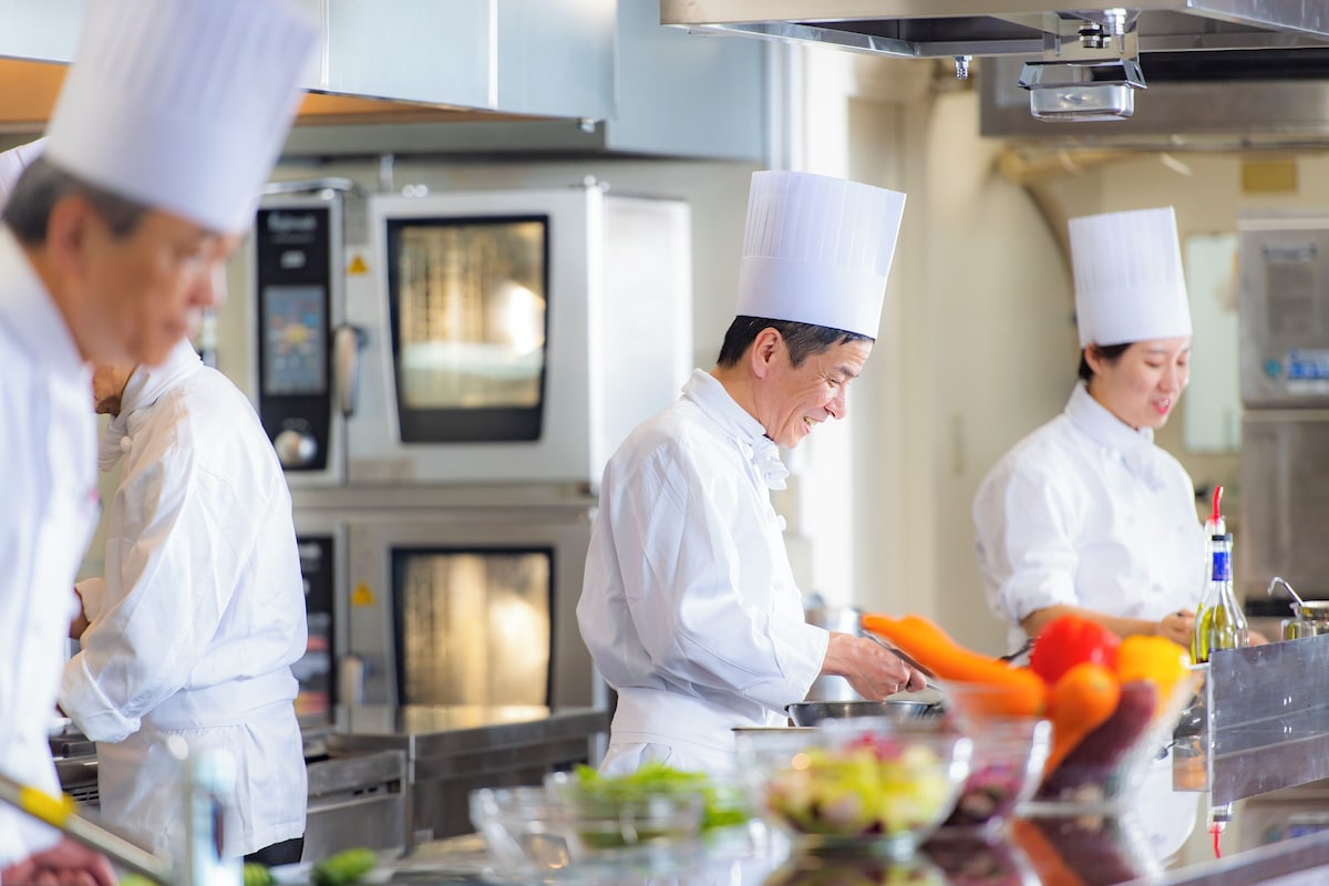 Three chefs preparing food in the breakfast kitchen at Hotel Shiragiku