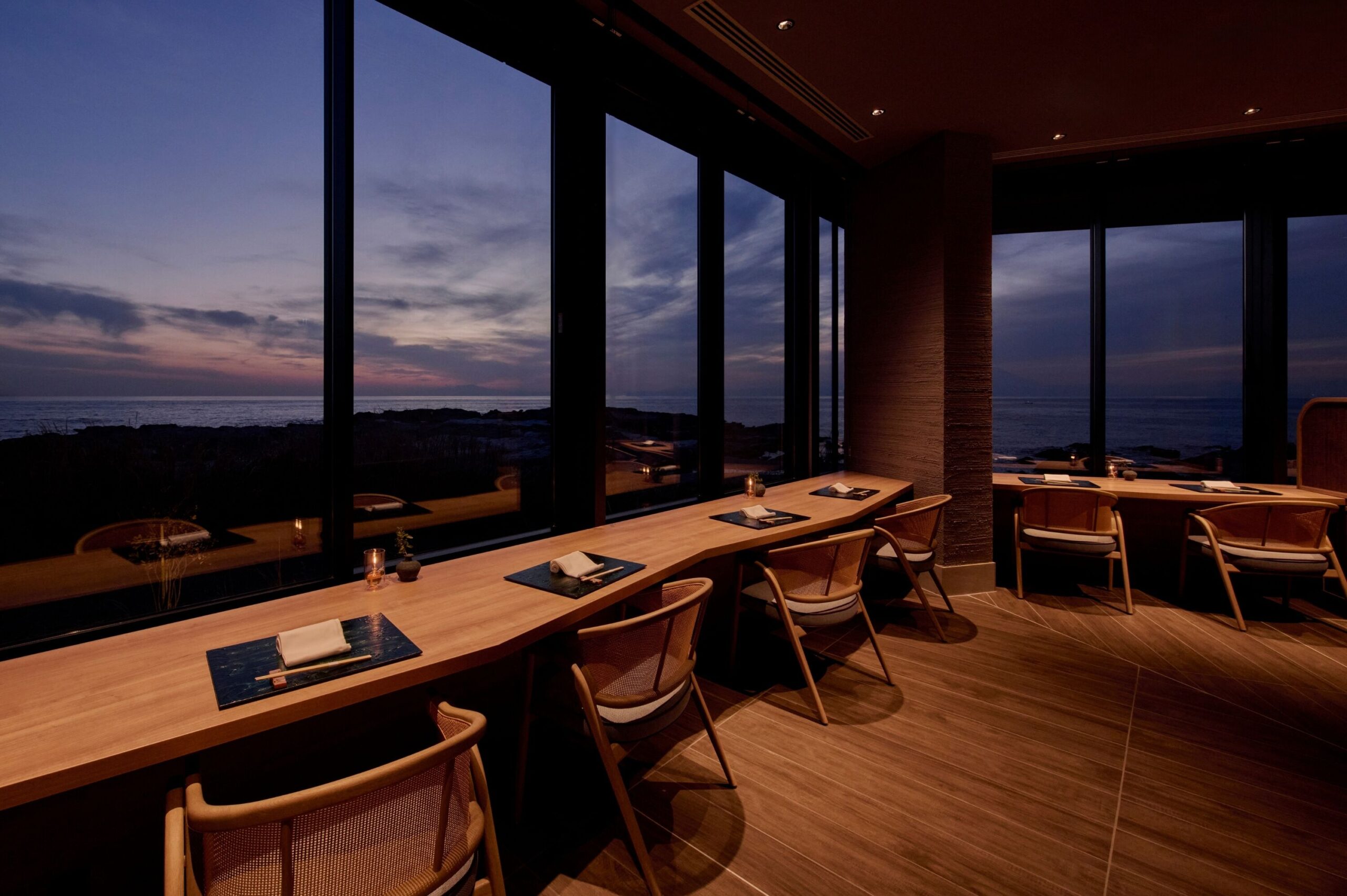 Sea-view counter seating in the restaurant at FUFU Jogashima at dusk.