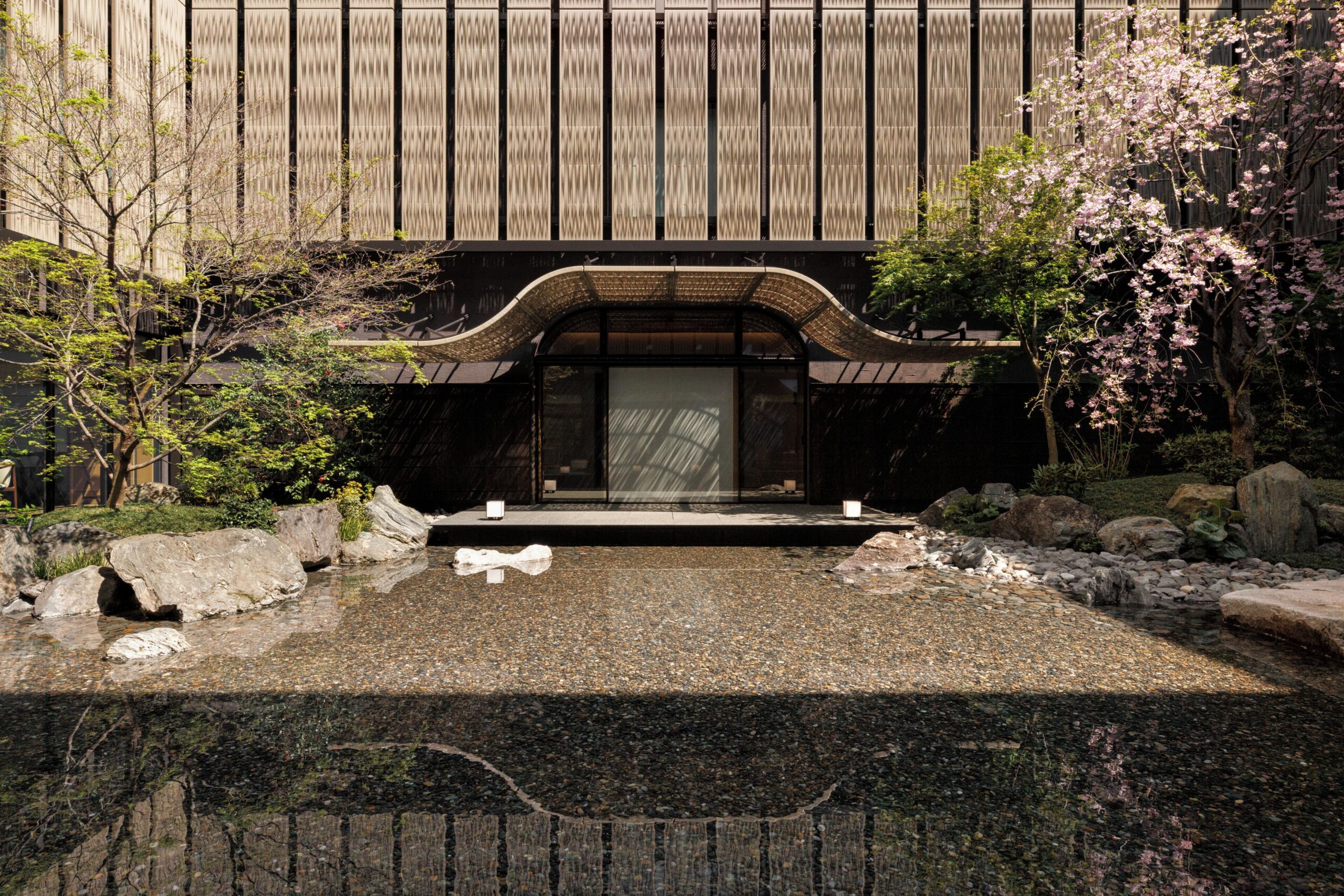 Water garden, rocks and trees beneath the curved canopy at Capella Kyoto