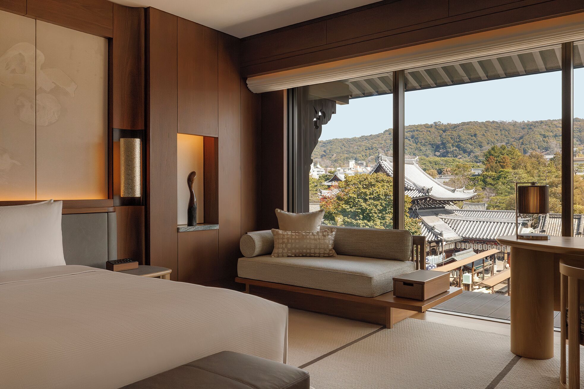 Guestroom at Capella Kyoto with a window seat overlooking tiled roofs and wooded hills