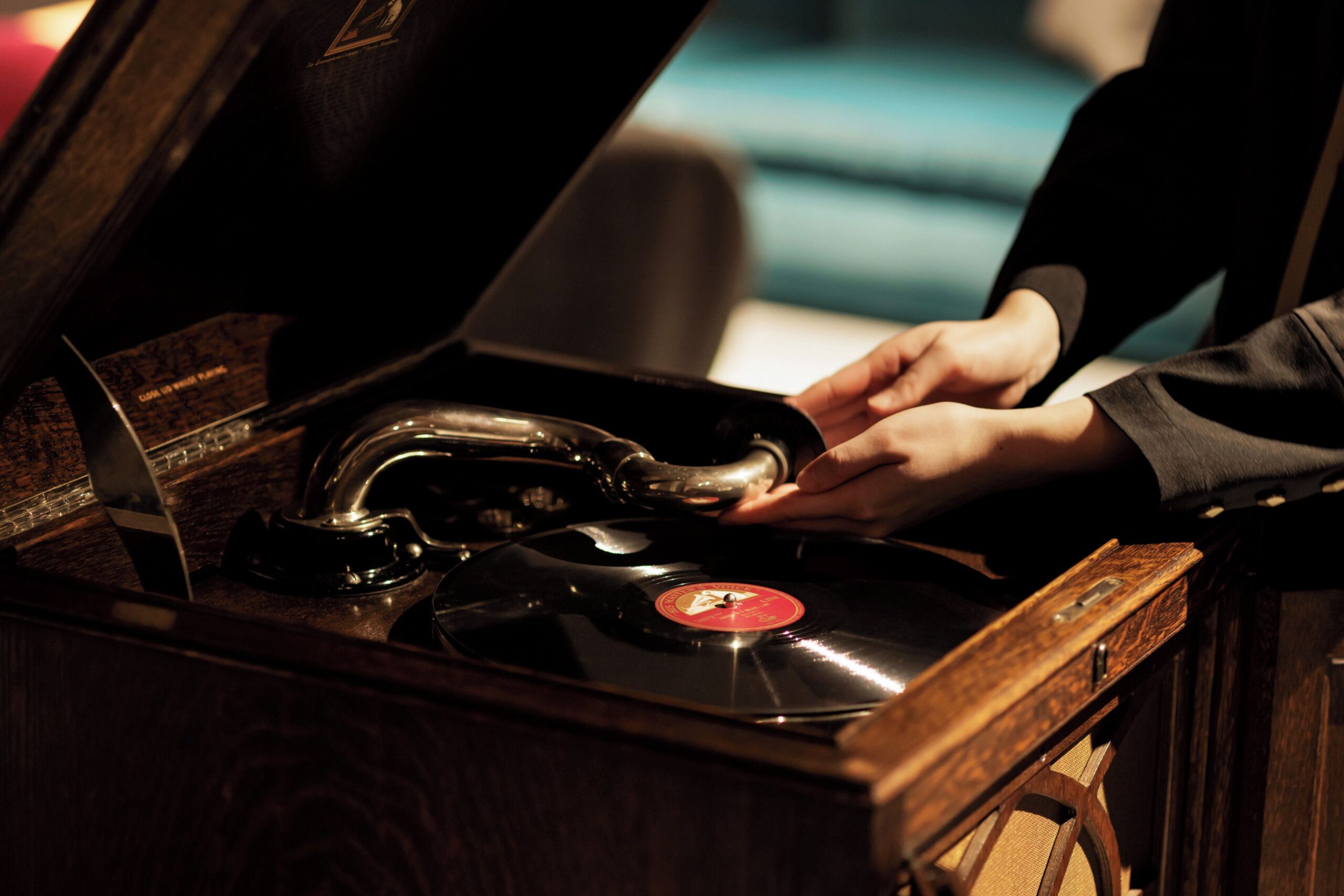 Hands beside a record on a wooden gramophone at HOSHINOYA Nara Prison