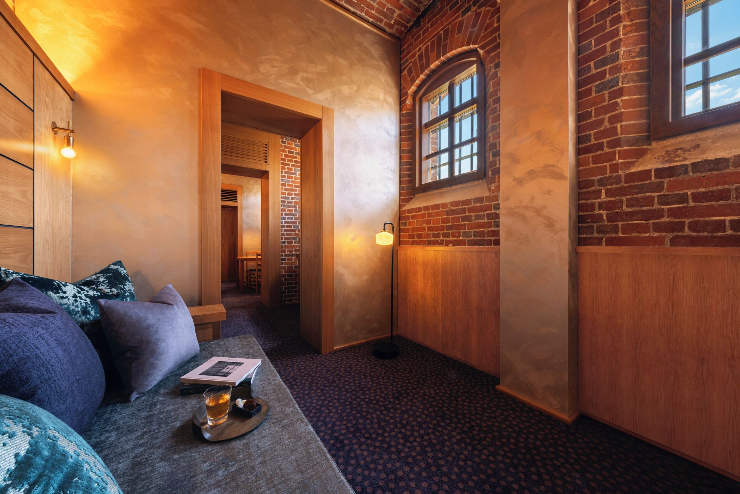 Sofa, exposed brickwork and high windows in a suite at HOSHINOYA Nara Prison